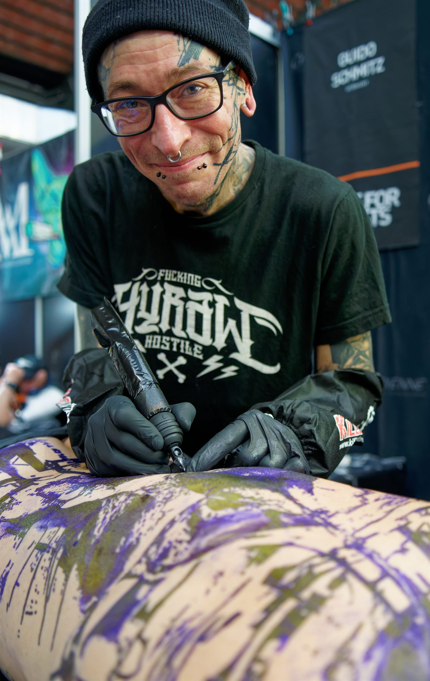 Tatuador aplicando tatuagem em cliente no estúdio